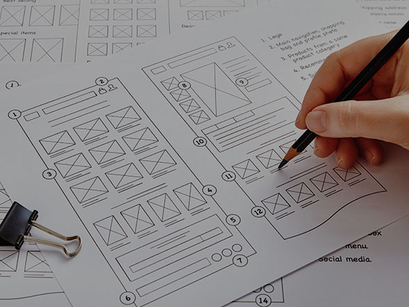 Designer sketching wireframe concepts for web design showing site structure and layout.
